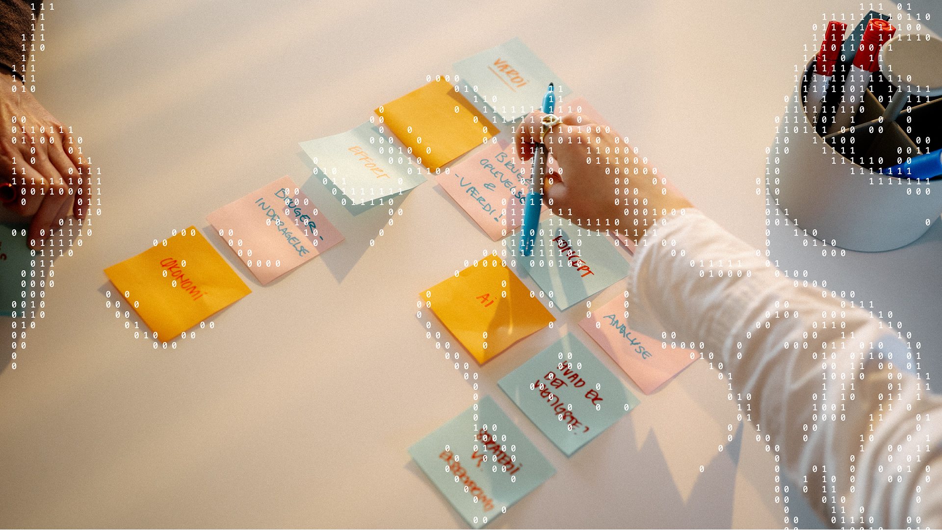 Nærbillede af post-its på et bord med håndskrevne ord som 'AI', 'analyse' og 'økonomi'. En hånd skriver på en seddel. Binær kode er lagt hen over billedet som grafisk element.
